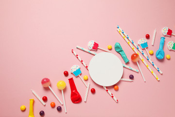 Children's birthday pink background. Scattered colorful candies, balls, candles and straws.