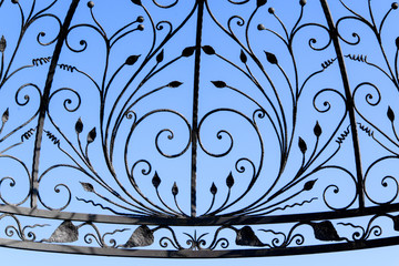 Fototapeta na wymiar Fragment of iron wrought fence with beautiful artistic shape