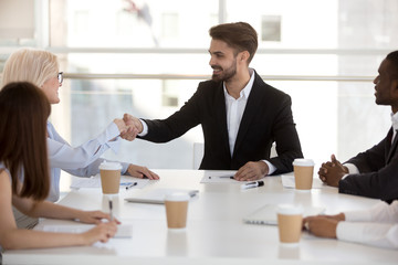 Businesswoman shaking hands with company client at meeting in office