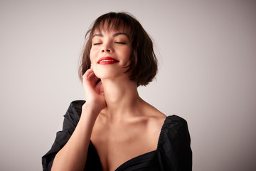 Close-up portrait of young woman with closed eyes daydreaming at light background