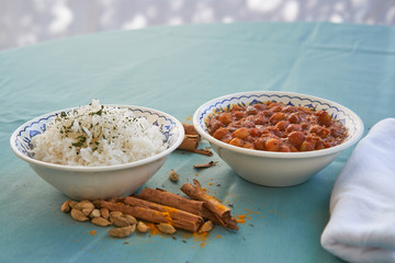 Indian vegetarian food spicy hot chickpea curry with basmati rice served in bowls on green tablecloth with cinnamon sticks, cardamom seeds and curry powder. Indian vegan cuisine, spicy, light, health