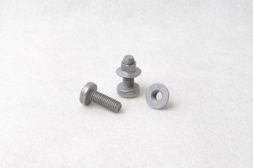 Screws and nuts on white cloth