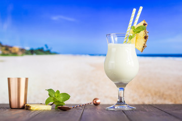 Cold pina colada cocktail in a glass on the beach with seascape background