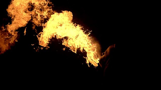 fakir in complete darkness spits fire up.