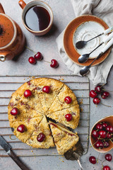 Homemade cherry crumble pie with fresh berries on rustic background, top view