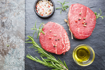 Raw marbled meat steak Filet Mignon with seasonings over stone background, top view.