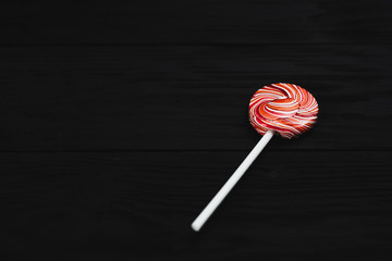 red, round colored Lollipop on black background