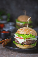 Hamburger with beef meat burger and fresh vegetables on dark background. Tasty fast food.