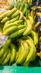 The fresh green bananas are in the boxes on the counter of the supermarket