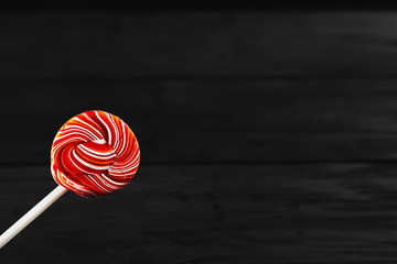 red, round colored Lollipop on black background