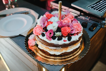 Cake decorated with many flowers on a table.