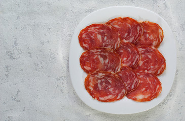 Slices of smoked sausage prosciutto or salami beautifully laid out on a white plate. The view from the top. Copy space.