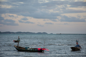 Thai fisher stopping wooden fishery boat floating and stop wait for go to catching fish in the sea in evening time in Rayong, Thailand