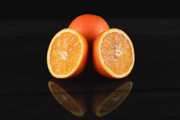 Fresh fruit oranges on black wooden background with reflection