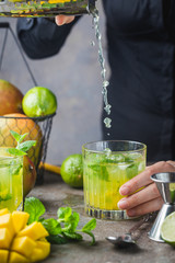 Fresh mango mojito cocktail with lime and mint in a glass