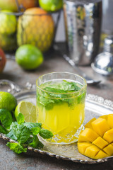 Fresh mango mojito cocktail with lime and mint in a glass