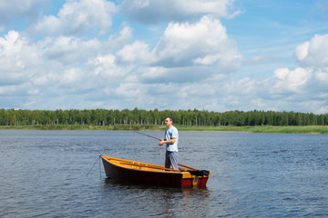 Fototapeta na wymiar a man standing in a boat fishing for fishing on a lake in the forest