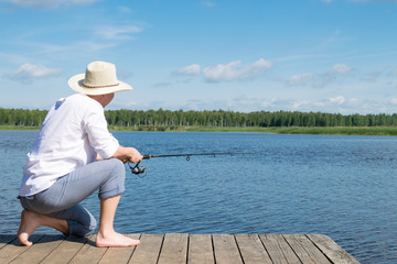 man catches fish from the shore of a beautiful lake in the forest