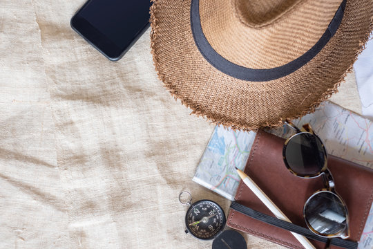 Top View Of Summer Brown Panama Straw Hat,mobile,sunglasses,notebook Map,compass On Linen Cloth.vacation Travel Concept.copy Space For Adding Text.