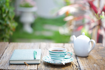 Blue stripes cup pattern with white kettle on and notebook on wooden table