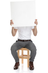 casual man covers his face with a blank board