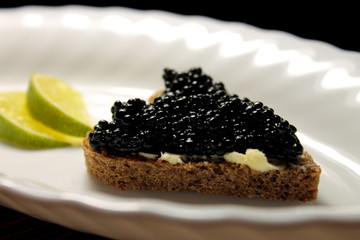 Black caviar on a piece of bread on a plate close-up