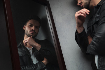 pensive young man looks in the mirror