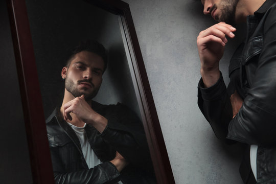 Pensive Young Man Looks In The Mirror