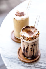 Two glasses of iced latte on marble background.