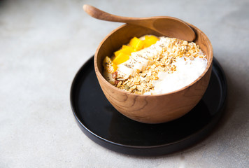 Mango smoothie bowl with strawberry and coconut and oatmeal on the table.
