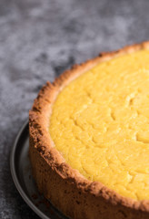 Tasty homemade vegan lemon cheesecake on dark gray stone plate