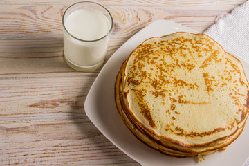 A big pack of delicious pancakes on a white plate with milk