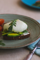 sandwich with avocado, poached egg, arugula and cherry tomatoes
