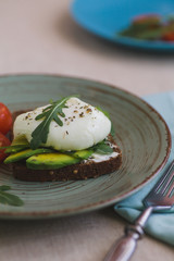 sandwich with avocado, poached egg, arugula and cherry tomatoes