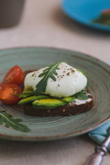 sandwich with avocado, poached egg, arugula and cherry tomatoes