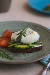 sandwich with avocado, poached egg, arugula and cherry tomatoes