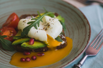 sandwich with avocado, poached egg, arugula and cherry tomatoes