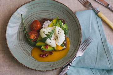 sandwich with avocado, poached egg, arugula and cherry tomatoes