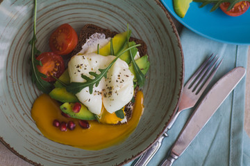sandwich with avocado, poached egg, arugula and cherry tomatoes