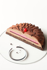 Contemporary Chocolate Cherry Mousse Cake covered with velvet spray, on white background. 