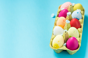 Easter eggs are painted in bright colors, lie in a cardboard eco-packaging. Blue background. Easter ideas. Space for text. Egg eco tray. Happy easter.