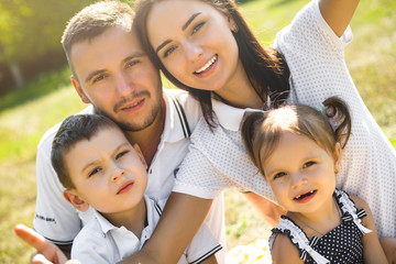 Cheerful young family making selfie at the picnic outdoor. Beautiful family together having fun. Day off with children. Young parents with their kids making mobile picture.