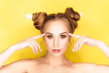 Young beauty girl with hair horns electic lamp hairstyle on a yellow background
