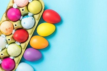 Easter eggs are painted in bright colors, lie in a cardboard eco-packaging. Blue background. Easter ideas. Space for text. Egg eco tray. Happy easter.