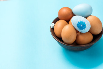 Easter eggs of brown color lie in a dark clay plate on a beautiful blue background. Easter ideas. Space for text. Happy easter.