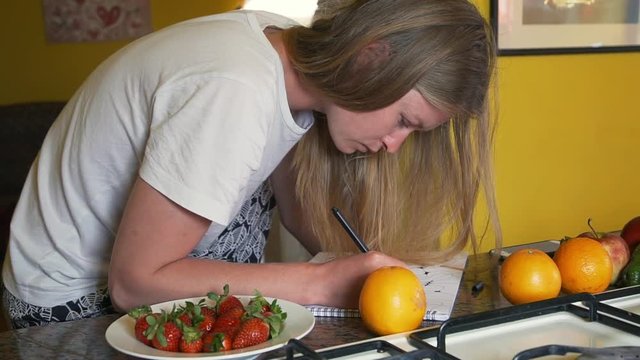 Young handsome female draw some scatch sitting in wide kitchen slow motion