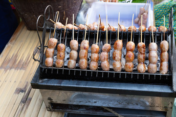 Thai sausage (Thai name  Sai Krok Isan), made from mince pork, rice. Mix all together, stuffed in pork chitterlings,Thai sausage on the stove. Thailand street food. pork sausage served with vegetables