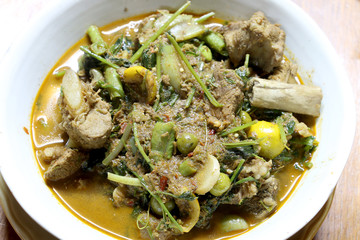 Northern Thai spicy curry with pork and mixed vegetables and Thai herbs with a Northern Spices in white blow on wooden table, Kaeng khae in Thai word, Northern style Curry,Thai northern style food.