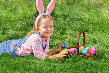 Cute little girl child with basket on green grass in the park. Easter Egg Hunting Concept