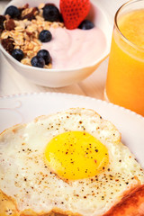 Breakfast of sunny side up eggs, sausages, orange juice, and fruits , vertical composition